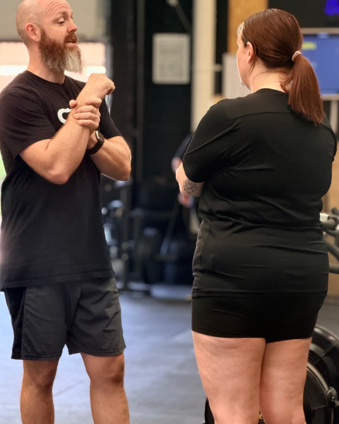 A coach demonstrating a stretch to a member in a personal training session